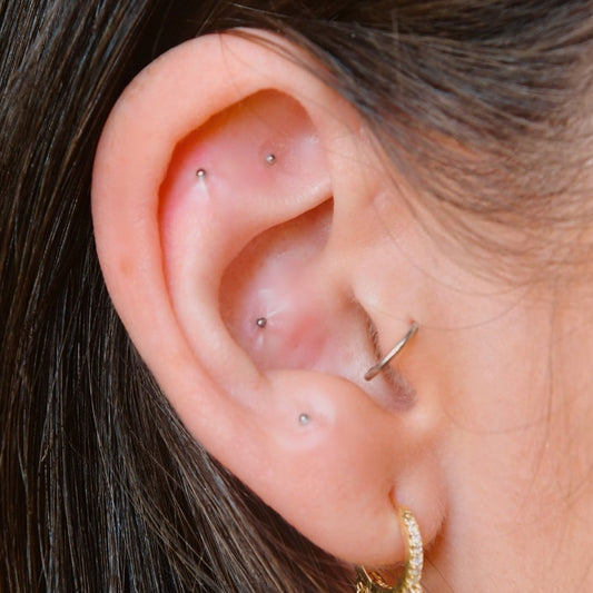 NAO Wellness Stainless Steel 20-pc Ear Seed Kit - showing possible placement on model's ear. Additional ear adornments not included.